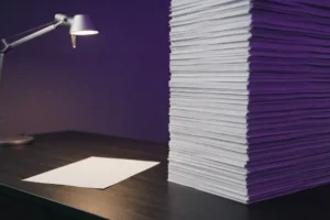 Pilha de currículos idênticos sobre mesa de escritório representando candidaturas geradas por IA